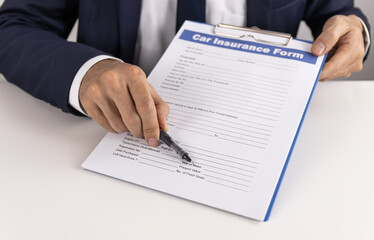 Insurance Agent Point Car Insurance Claim Form or Insurance Document on Office Table for Customer Sign