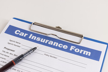 Car Insurance Claim Form or Auto Insurance Document and Pen at Left Frame and Clipboard on White Office Table