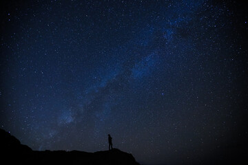 Silhouette of  boy / man on the hill. Stargazing at Oahu island, Hawaii. Starry night sky, Milky Way galaxy astrophotography.	