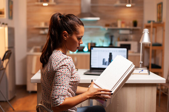 Freelancer architect working in home office during night time holding a building model for a client. Engineer artist creating and working in office holding scale building model, determination, career.