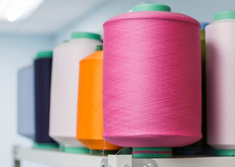 Rows of coils on a shelf with threads of different colors in the knitting industry