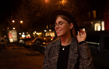 Young fashion woman walking on city street at night .