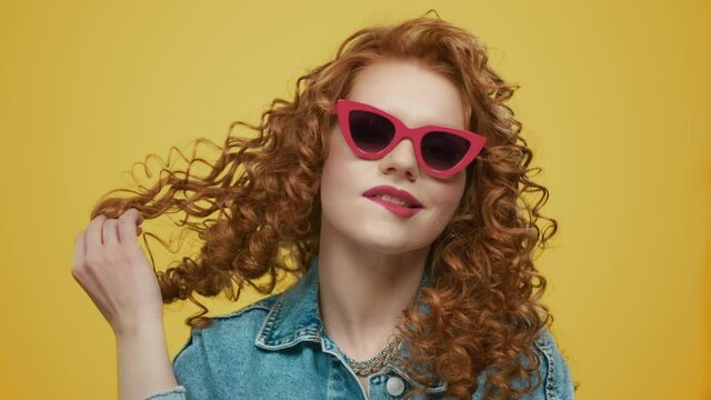 Woman wearing stylish sunglasses. Sexy lady pouting lips on yellow background