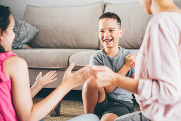 joyful family plays funny game joining hands near soft sofa in light living room.