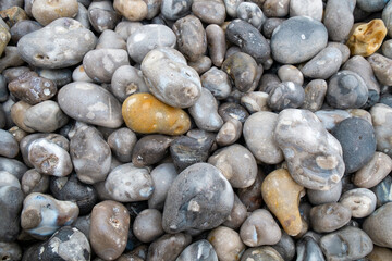 Close up of the pebbles on a beach in Normandy France, creating an Abstract smooth round pebbles sea texture background 