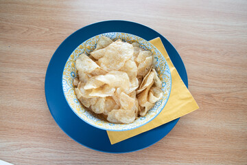 Potato chips fast junk food on blue bowl and wooden table