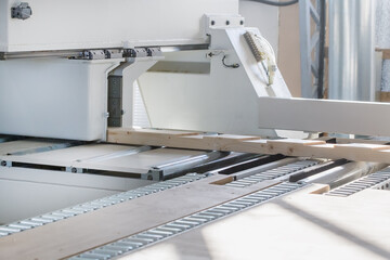 A board for a frame house lies in a woodworking machine. Woodworking industry. Selective focus on the board.