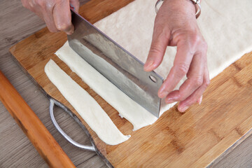 The chef cut the pie-shaped fried dough noodle into long strips with a knife