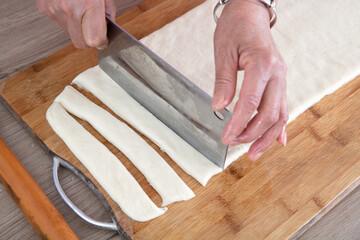 The chef cut the pie-shaped fried dough noodle into long strips with a knife