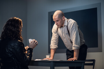 A cheeky guy suspected of a crime tears up documents during an interrogation in front of an...