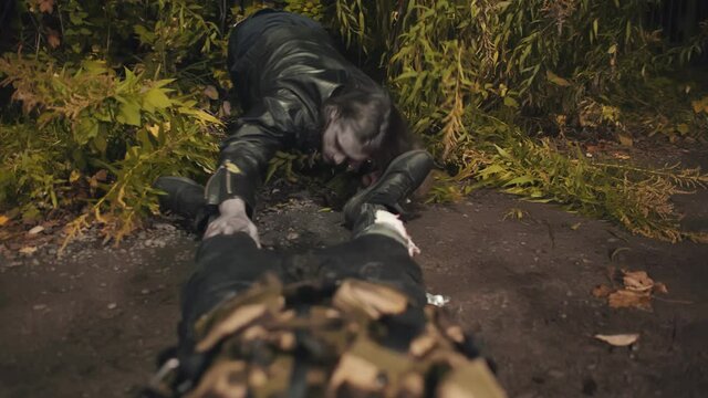Zombie eating dead man lying on ground outdoors
