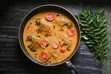 Top view spicy Kerala Style Fish stew and Appam Fish Molee or Meen Moilee Indian food. Fish curry with coconut milk red chili, curry leaf, tomato. Asian cuisine. Delicious hot Bengali, Goan fish curry