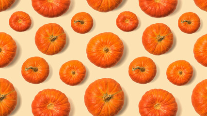 Seamless pattern of pumpkins of different sizes on a yellow background.