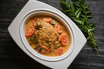 Top view spicy Kerala Style Fish stew and Appam Fish Molee or Meen Moilee Indian food. Fish curry with coconut milk red chili, curry leaf, tomato. Asian cuisine. Delicious hot Bengali, Goan fish curry