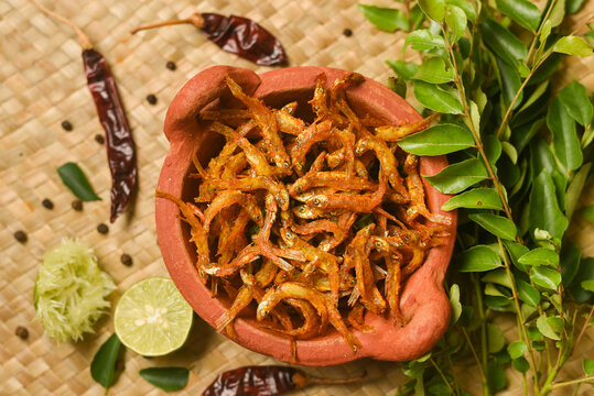 Top view of spicy hot anchovy fry Kerala fish curry. Indian food. Fried golden anchovies with red chili powder, curry leaf. Asian cuisine. Delicious spicy Bengali , Goan fish curry in clay pot
