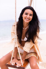 Happy smiling woman on swing at beach,day warm light. 