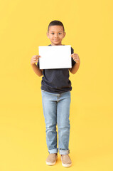 Little African-American boy with blank paper sheet on color background
