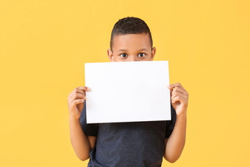 Little African-American boy with blank paper sheet on color background © Pixel-Shot