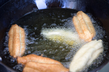 Deep-fried dough sticks in a hot oil pan