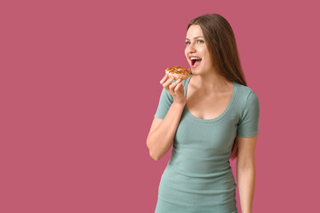Beautiful young woman with sweet donut on color background