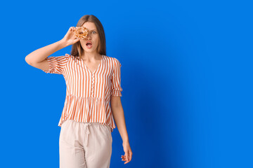 Surprised young woman with sweet donut on color background