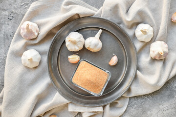Bowl with aromatic powdered garlic on grunge background