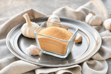 Bowl with aromatic powdered garlic on table