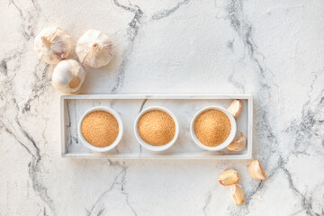 Bowls with aromatic powdered garlic on white background