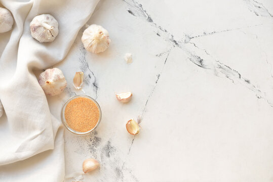Bowl with aromatic powdered garlic on white background