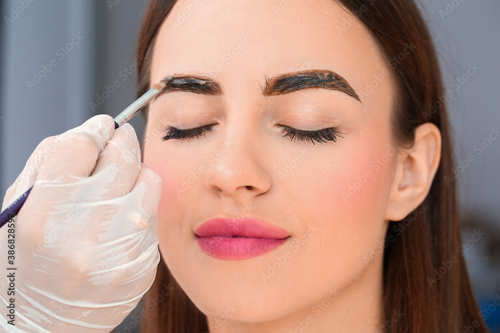 Sticker Young woman undergoing eyebrow correction procedure in beauty salon