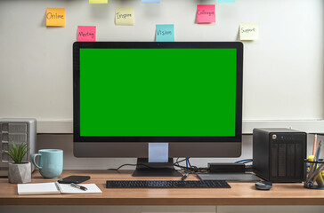 Computer desktop with Stationery and device showing the green screen via video conference when Coronavirus outbreak, Covid-19 pandemic,home office and new normal Concept
