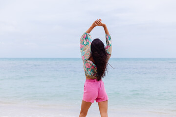 Happy woman with long hair in pink shorts enjoy time on beach by sea  