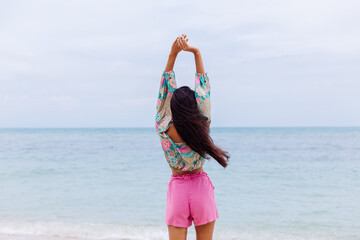 Happy woman with long hair in pink shorts enjoy time on beach by sea  