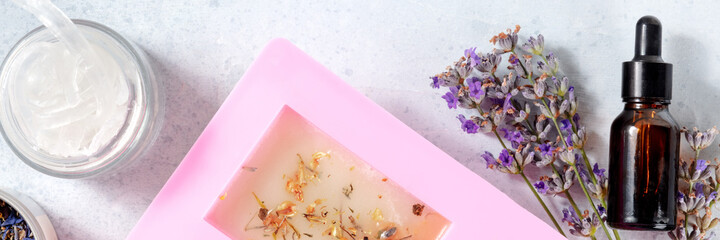 Handmade soap ingredients panorama. Glycerin, lavender flowers, essential oil, and soap in a mold, overhead shot