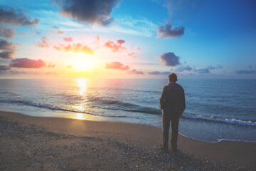 Silhouette of man on the beach. Man looking at magical sunset. Summertime. Twilight time on the beach. Seascape. Calm sea