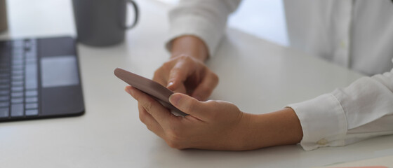 Female hands using smartphone on white table in workplace