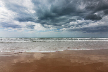 In riva al mare; in spiaggia, sul bagnasciuga in una giornata temporalesca d’estate