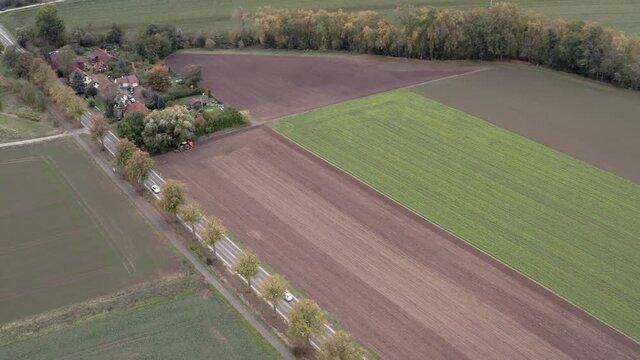 Drone aerial tracking shot of a german farmer harvesting his field in late autumn.