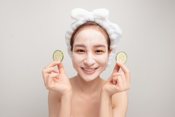 Cosmetic procedures. Woman with cosmetic mask on face eats cucumber slice.