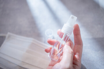 部屋で携帯用の消毒液スプレーを手で持つ様子。