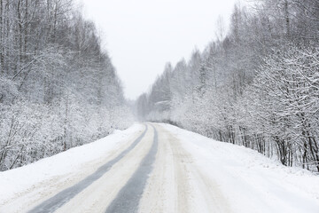 Fototapeta premium First snow, road after snowfall. Snowy road in the forest