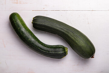two green zucchini on a white wooden table