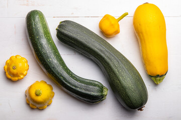 green and yellow zucchini and pattypan squashes on a white wooden table