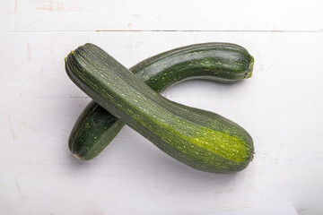 two green zucchini on a white wooden table