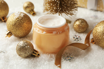 Fototapeta na wymiar Jar of cosmetic cream and Christmas accessories on background with decorative snow