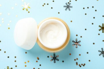 Cosmetic cream on blue background with glitter