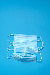 Stack of Disposable blue medical face masks on blue background