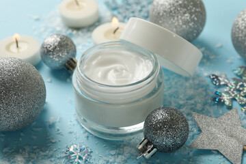 Fototapeta na wymiar Jar of cosmetic cream and Christmas accessories on blue background