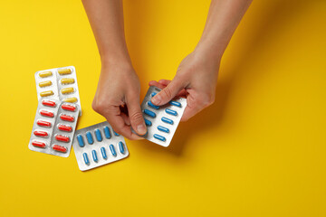 Female hands hold blister pack with pills on yellow background