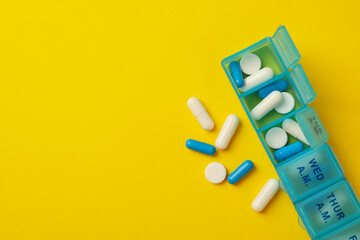 Plastic containers with pills on yellow background